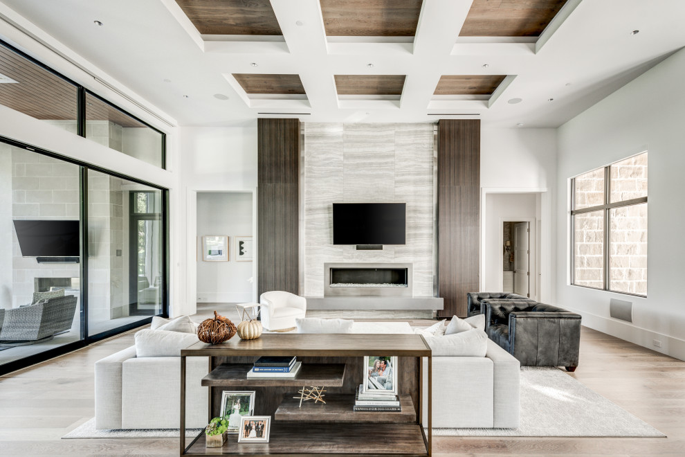 Photo of a classic formal open plan living room in Dallas with white walls, medium hardwood flooring, a standard fireplace, a stone fireplace surround, a wall mounted tv and brown floors.