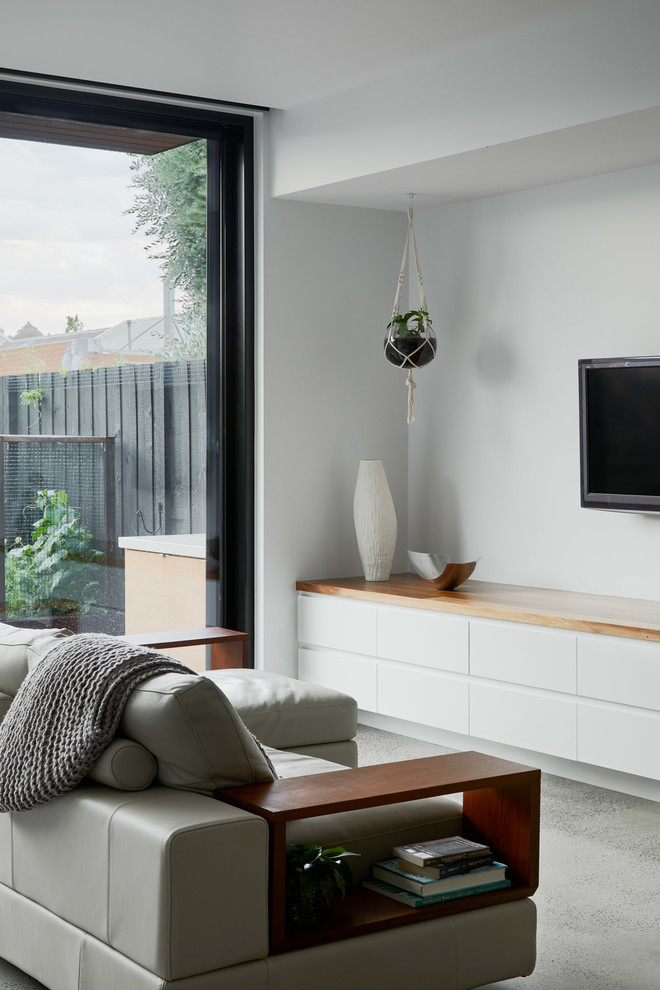 Пример оригинального дизайна: открытая гостиная комната среднего размера в современном стиле с белыми стенами, бетонным полом, телевизором на стене и серым полом