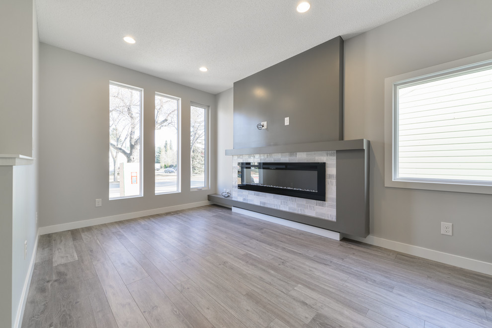Mittelgroßes, Offenes Modernes Wohnzimmer mit grauer Wandfarbe, Vinylboden, Gaskamin und grauem Boden in Edmonton