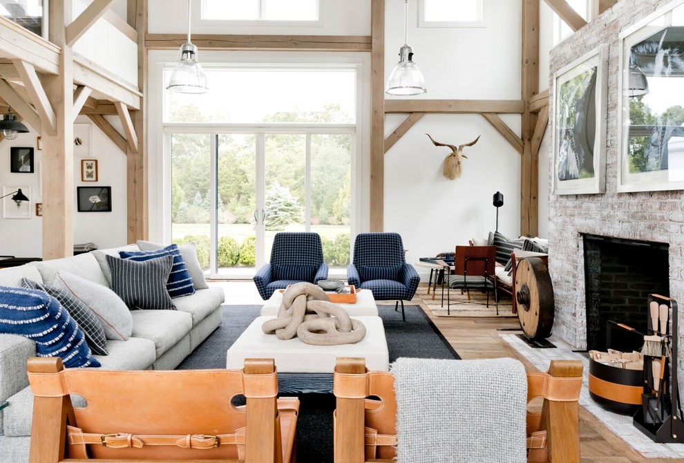 Inspiration for an expansive rural open plan living room in New York with white walls, light hardwood flooring, a standard fireplace, a brick fireplace surround and brown floors.