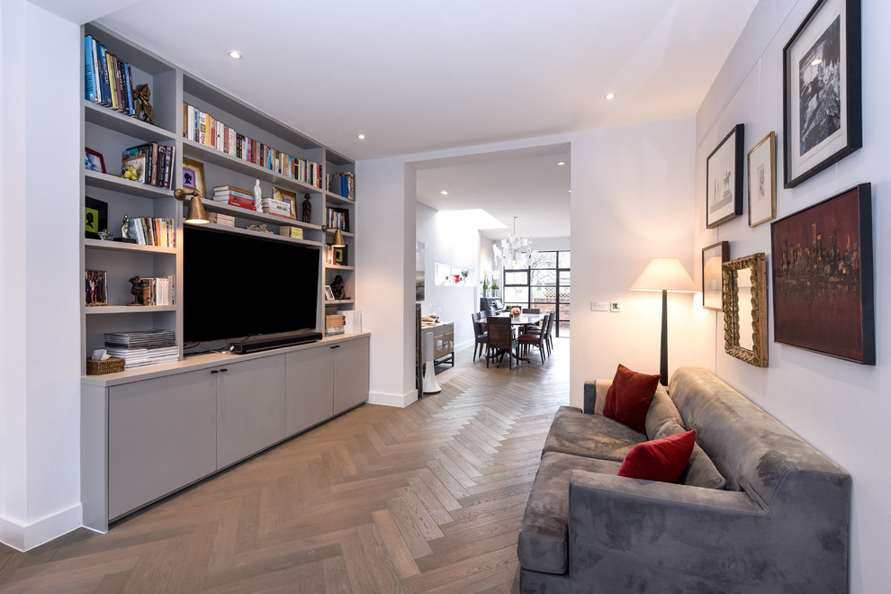 Immagine di un soggiorno minimal con pareti bianche, pavimento in legno massello medio, parete attrezzata e pavimento marrone