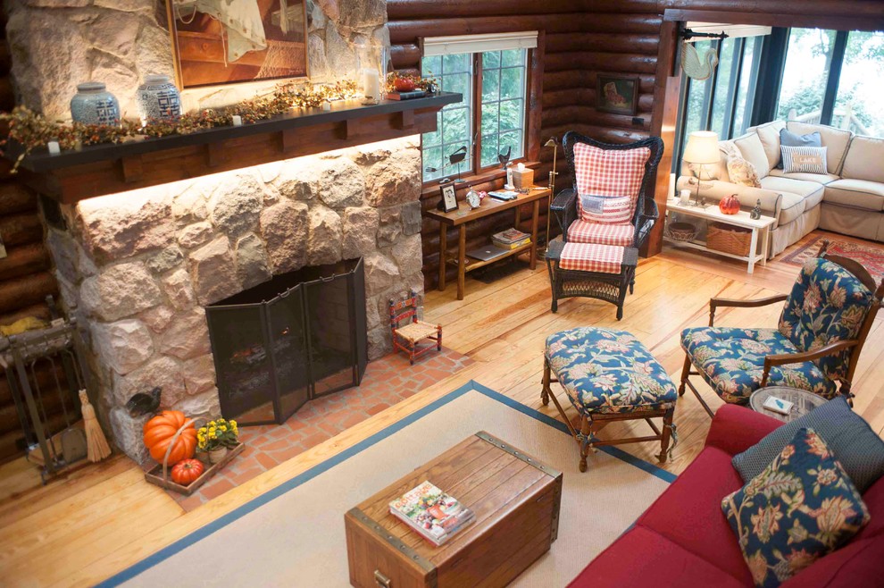 This is an example of a medium sized rustic open plan living room in Detroit with white walls, light hardwood flooring, a standard fireplace, a stone fireplace surround and no tv.