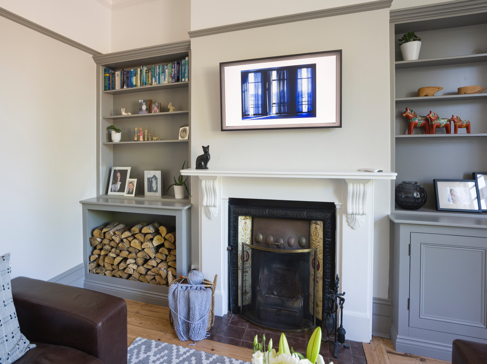 ロンドンにあるお手頃価格の中くらいなヴィクトリアン調のおしゃれな独立型リビング (グレーの壁、淡色無垢フローリング、薪ストーブ、タイルの暖炉まわり、壁掛け型テレビ、茶色い床) の写真