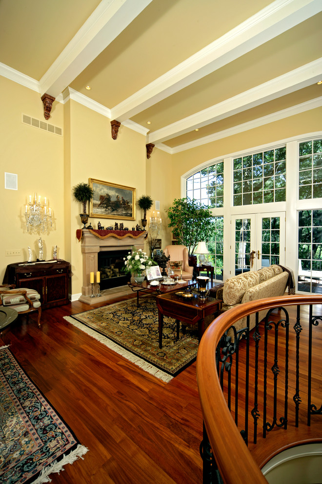 Imagen de salón para visitas abierto tradicional grande con paredes amarillas, suelo de madera en tonos medios y todas las chimeneas