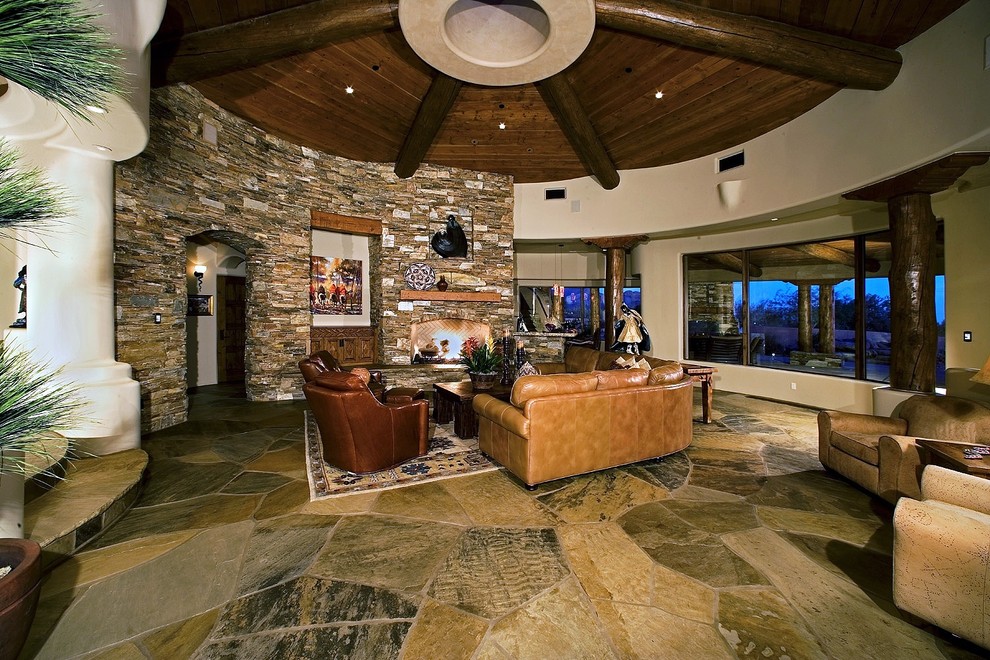 Large southwest open concept slate floor and beige floor living room photo in Phoenix with beige walls, a standard fireplace, a stone fireplace and a media wall