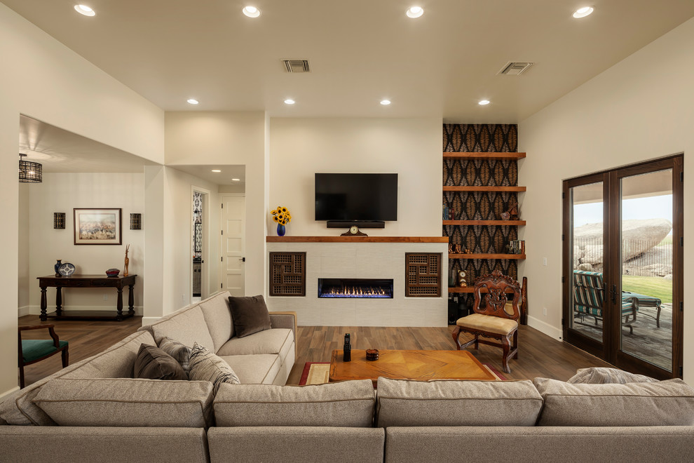 На фото: парадная, открытая гостиная комната среднего размера в стиле фьюжн с полом из керамической плитки, стандартным камином, фасадом камина из плитки, телевизором на стене, коричневым полом и белыми стенами