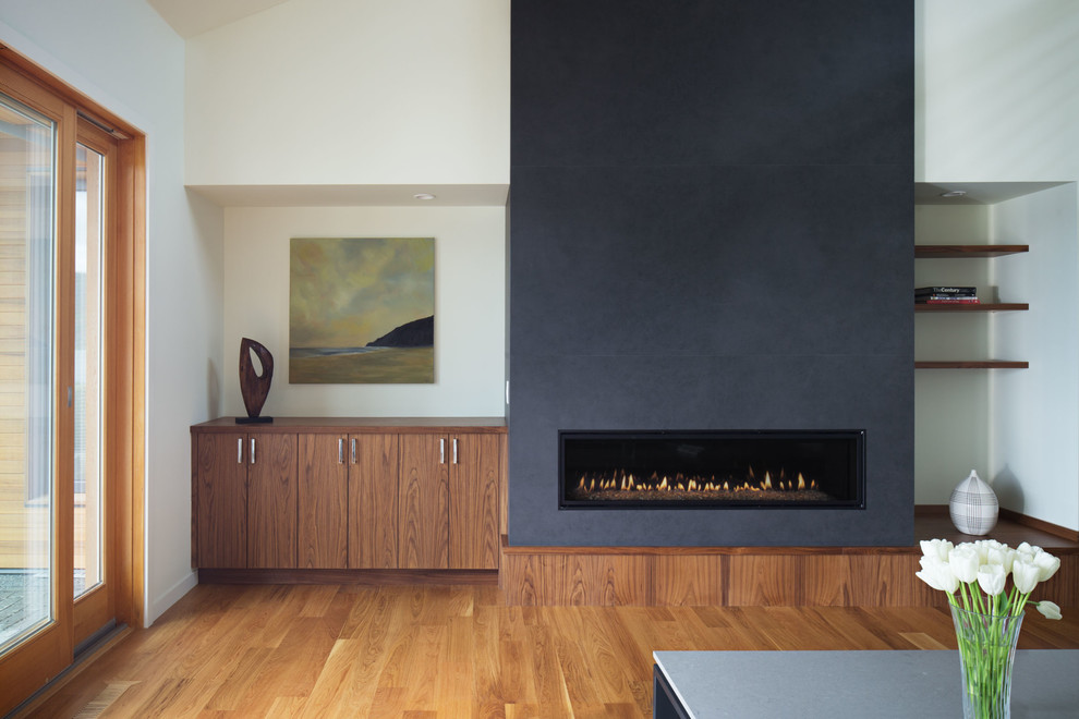 Offenes Modernes Wohnzimmer mit weißer Wandfarbe, braunem Holzboden, Kamin und gefliester Kaminumrandung in Seattle