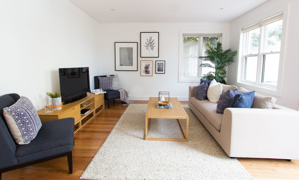 Diseño de salón abierto contemporáneo pequeño sin chimenea con paredes blancas, suelo de madera en tonos medios y televisor independiente