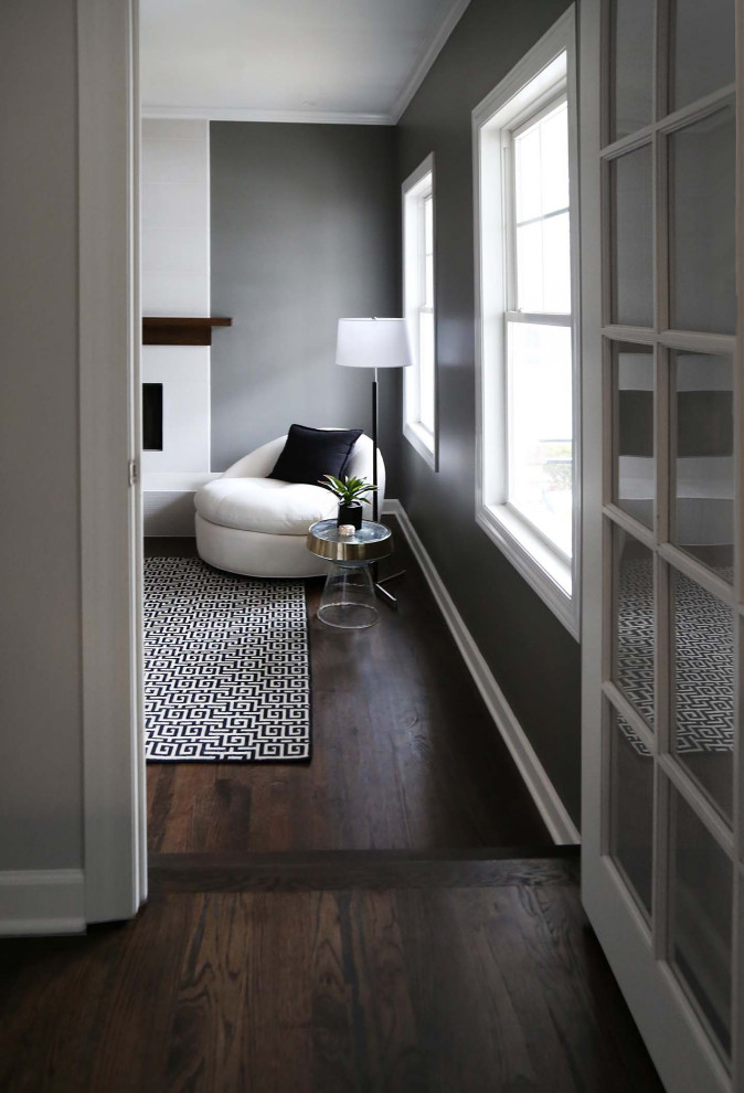 Esempio di un soggiorno tradizionale chiuso con pareti grigie, pavimento in legno massello medio, camino classico e pavimento marrone