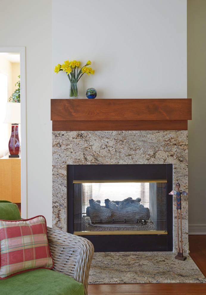 Aménagement d'un salon classique avec un mur blanc, un sol en bois brun, une cheminée double-face et un manteau de cheminée en carrelage.