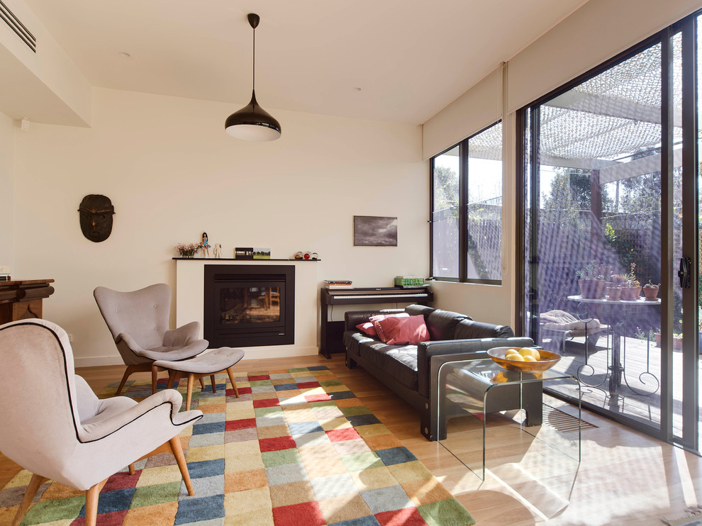 Mittelgroßes, Offenes, Fernseherloses Modernes Wohnzimmer mit weißer Wandfarbe, hellem Holzboden, Kamin und Kaminumrandung aus Metall in Melbourne