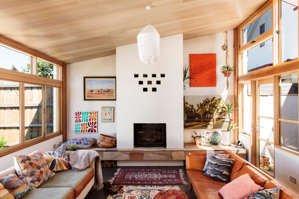 Inspiration pour un petit salon design ouvert avec un mur blanc, sol en béton ciré, un poêle à bois, un manteau de cheminée en brique et un téléviseur dissimulé.