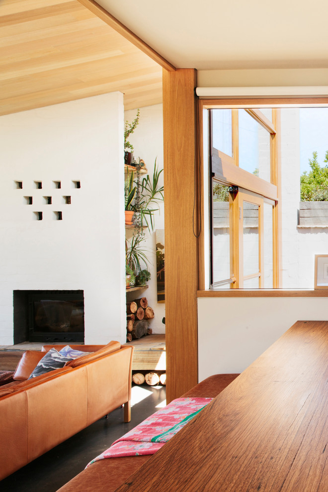 Foto di un piccolo soggiorno minimalista aperto con pareti bianche, pavimento in cemento, stufa a legna, cornice del camino in mattoni e nessuna TV