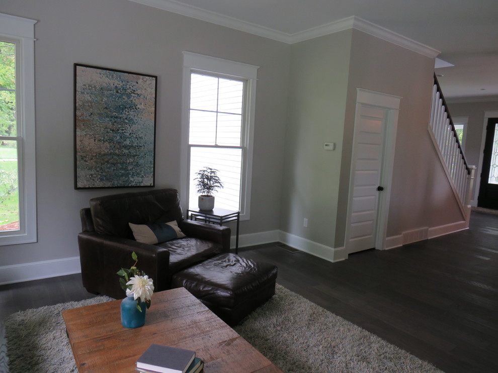 Großes, Offenes Landhaus Wohnzimmer mit beiger Wandfarbe, dunklem Holzboden, Kamin, Kaminumrandung aus Stein und TV-Wand in Grand Rapids