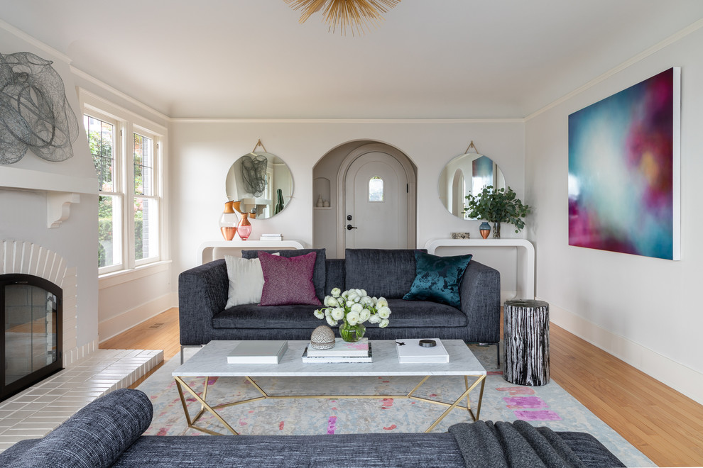 Mid-sized trendy enclosed medium tone wood floor and brown floor living room photo in Seattle with gray walls, a standard fireplace, a plaster fireplace and no tv