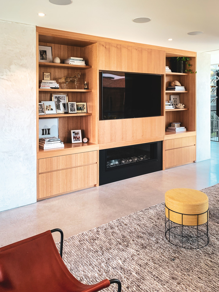 This is an example of a large open plan living room in Sydney with white walls, concrete flooring, a hanging fireplace, a concrete fireplace surround, a wall mounted tv and grey floors.