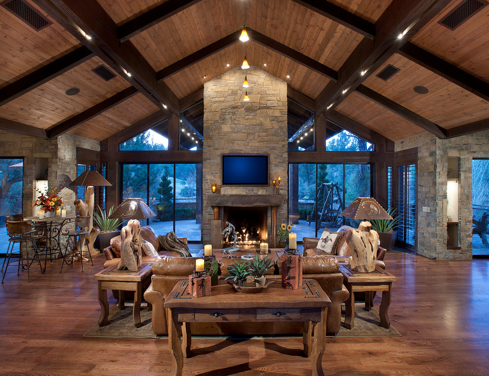Inspiration for a medium sized rustic open plan living room in Phoenix with medium hardwood flooring, a standard fireplace, a stone fireplace surround, a wall mounted tv and feature lighting.
