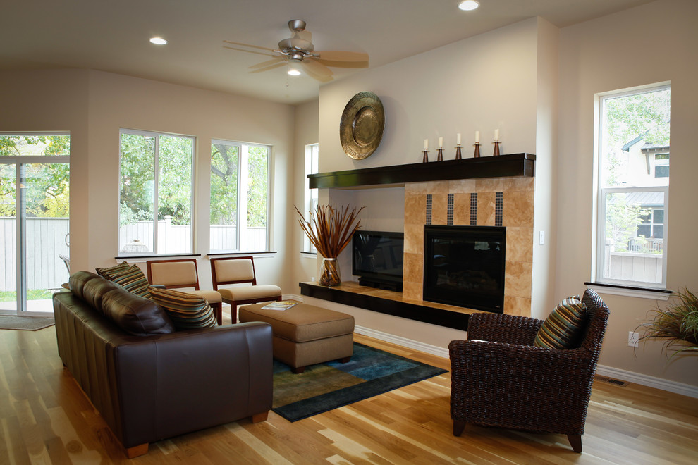 Cette image montre un salon design de taille moyenne et ouvert avec un mur beige, un sol en bois brun, une cheminée standard, un manteau de cheminée en carrelage et un téléviseur indépendant.