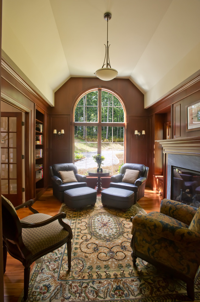На фото: изолированная гостиная комната среднего размера в классическом стиле с с книжными шкафами и полками, паркетным полом среднего тона, стандартным камином и фасадом камина из дерева