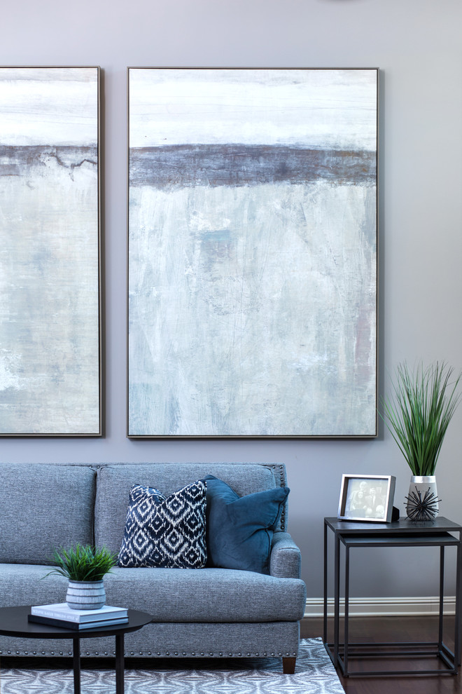 На фото: открытая гостиная комната среднего размера в стиле неоклассика (современная классика) с серыми стенами, темным паркетным полом, стандартным камином, фасадом камина из камня, телевизором на стене и коричневым полом с