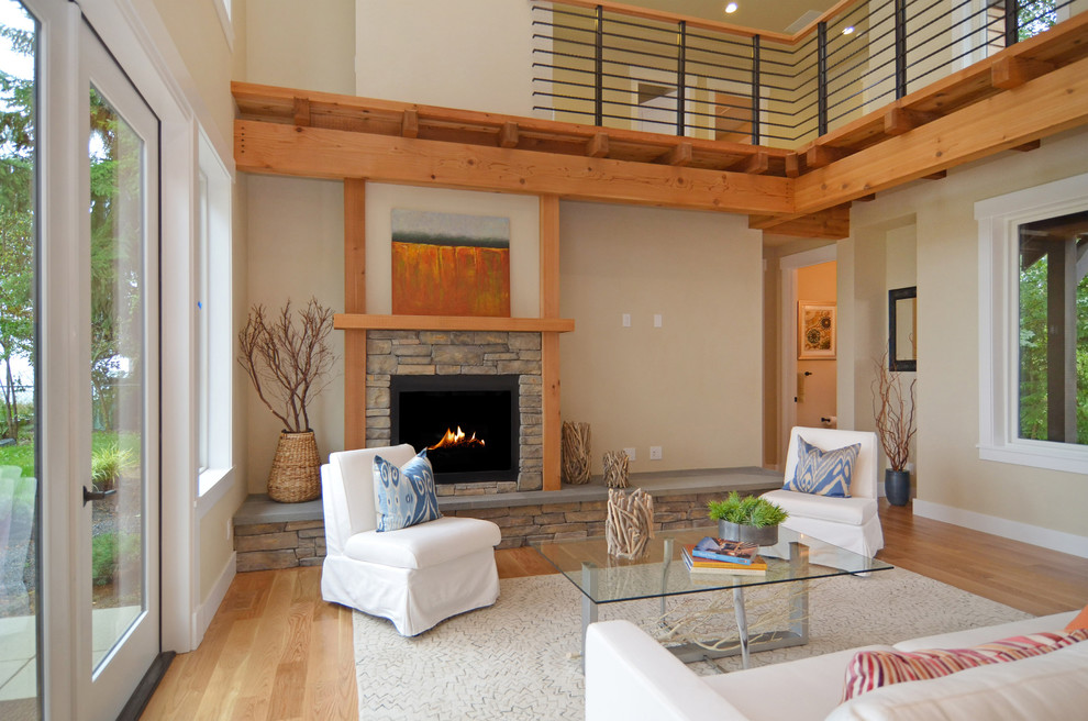 Foto de salón abierto de estilo americano grande con paredes beige, suelo de madera clara, todas las chimeneas y marco de chimenea de piedra