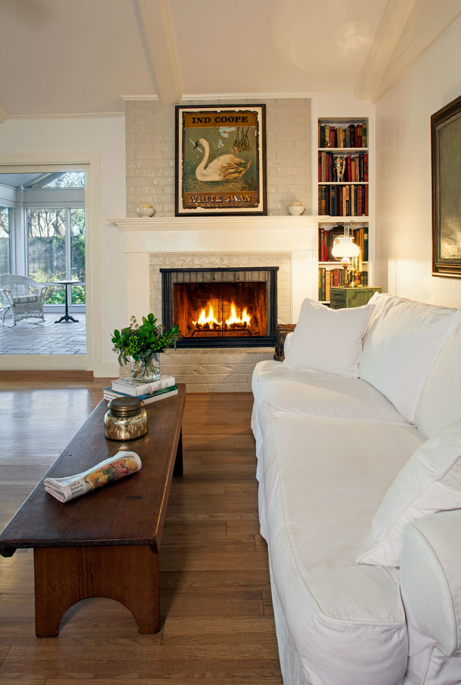 オースティンにある中くらいなトラディショナルスタイルのおしゃれなリビング (白い壁、無垢フローリング、標準型暖炉、木材の暖炉まわり、テレビなし) の写真