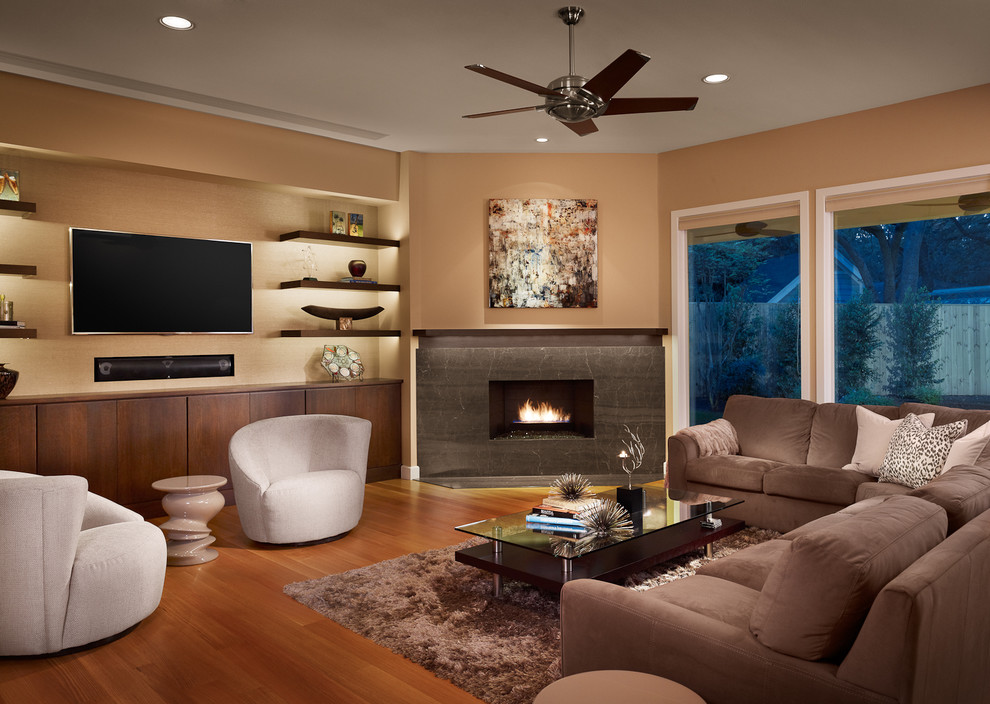 Großes, Offenes Modernes Wohnzimmer mit Eckkamin, beiger Wandfarbe, braunem Holzboden, Kaminumrandung aus Stein und TV-Wand in Austin