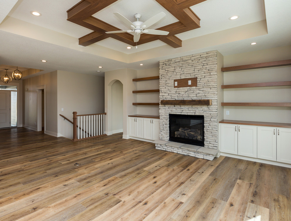 Country Wohnzimmer mit Vinylboden, Kamin, Kaminumrandung aus Stein und braunem Boden in Sonstige