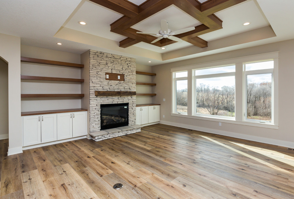 Landhaus Wohnzimmer mit Vinylboden, Kamin, Kaminumrandung aus Stein und braunem Boden in Sonstige