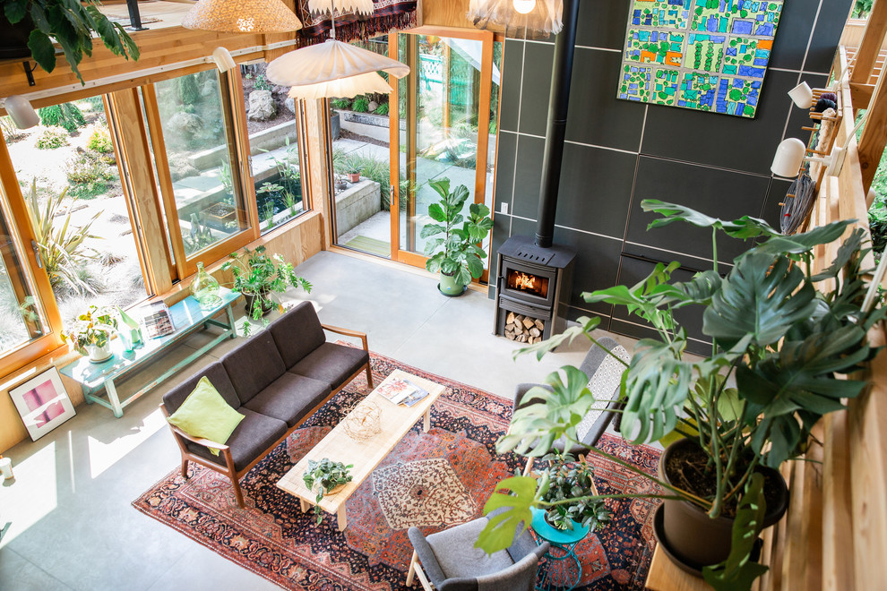 Immagine di un soggiorno minimal stile loft con pavimento in cemento e stufa a legna