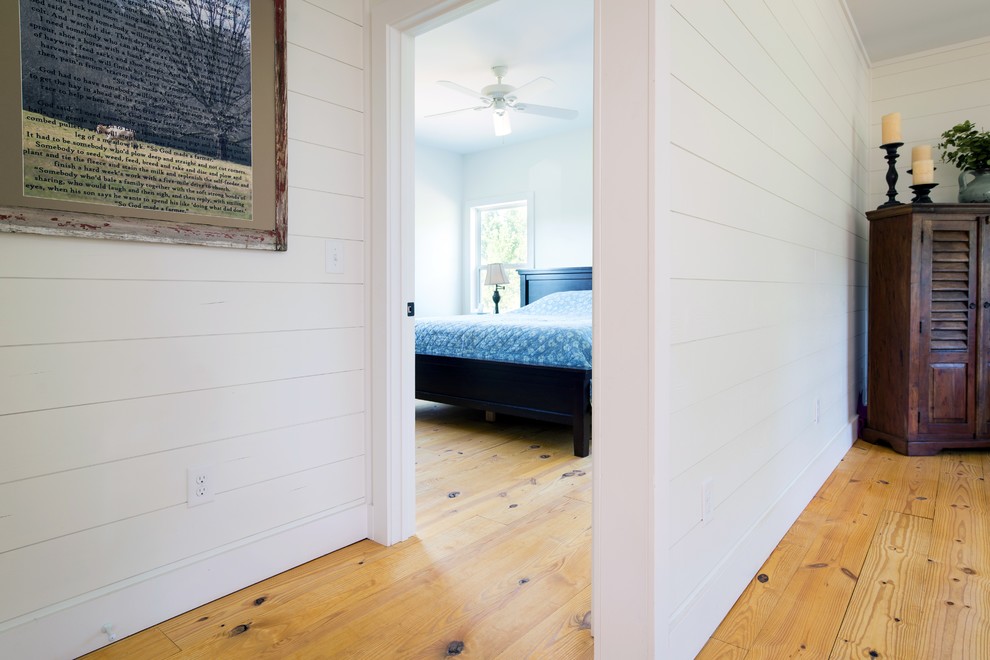 Diseño de salón campestre de tamaño medio con paredes blancas, suelo de madera en tonos medios y suelo marrón