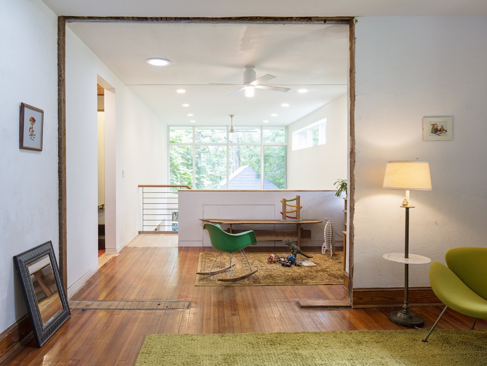 Immagine di un soggiorno design stile loft con pareti bianche, pavimento in legno massello medio e nessun camino