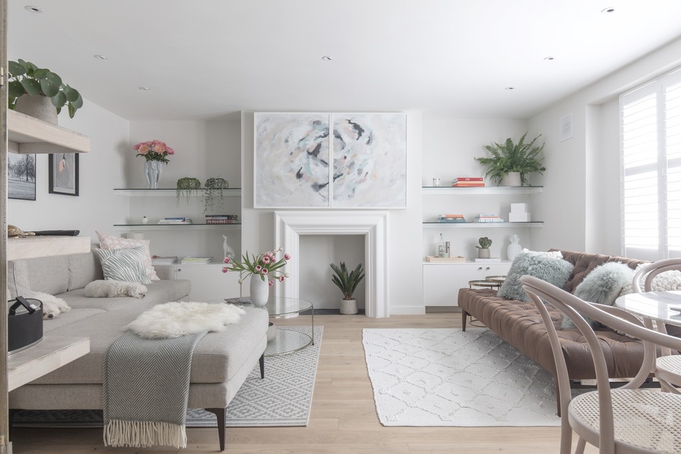 ロンドンにあるお手頃価格の小さな北欧スタイルのおしゃれなLDK (白い壁、淡色無垢フローリング、標準型暖炉、漆喰の暖炉まわり、内蔵型テレビ、茶色い床) の写真