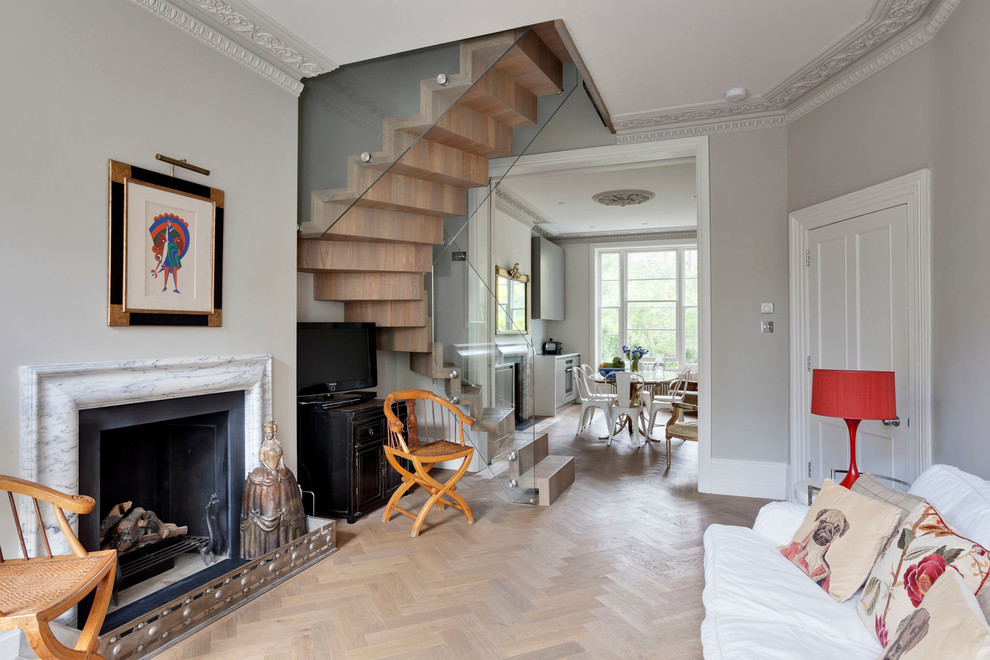 This is an example of a medium sized bohemian formal enclosed living room in London with grey walls, a standard fireplace, a stone fireplace surround, medium hardwood flooring, a freestanding tv and brown floors.