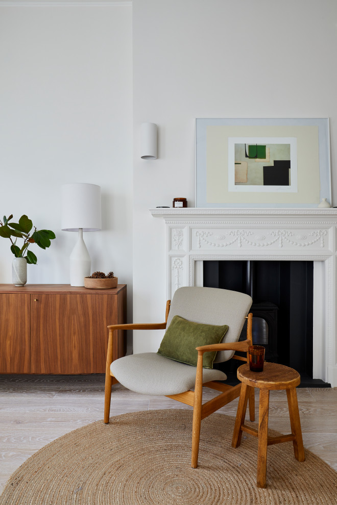 This is an example of a small midcentury open plan living room in London with white walls, light hardwood flooring, a wood burning stove and a metal fireplace surround.