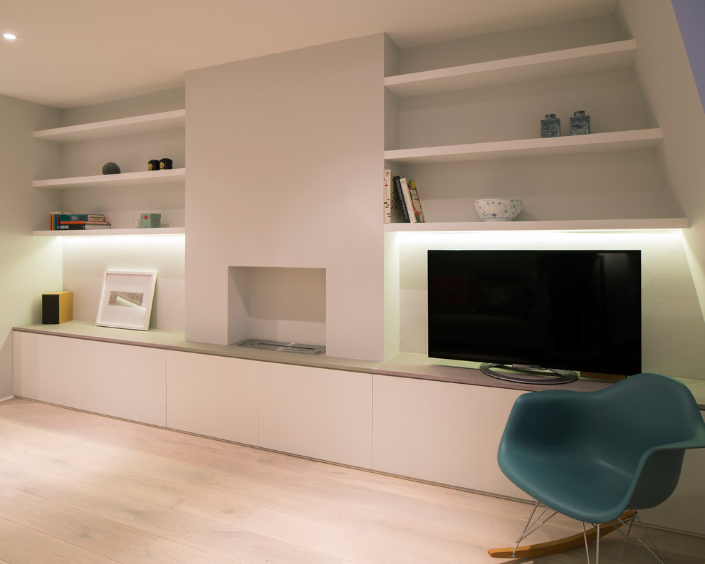 Modelo de salón abierto escandinavo pequeño con paredes blancas, suelo de madera clara, marco de chimenea de hormigón y televisor independiente