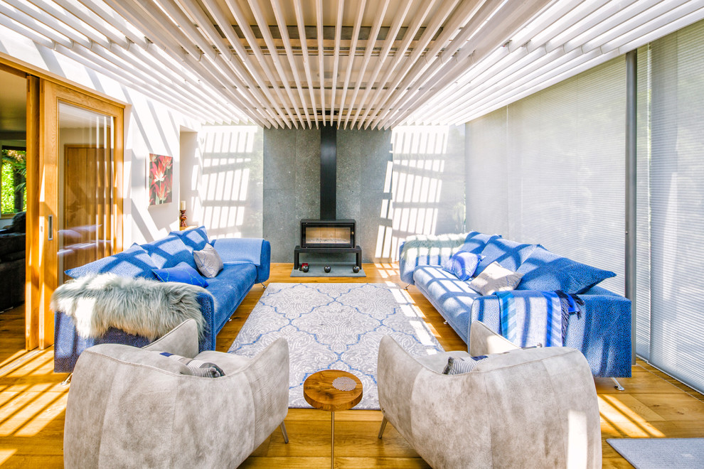 Diseño de salón para visitas abierto contemporáneo de tamaño medio sin televisor con paredes blancas, suelo de madera en tonos medios y estufa de leña