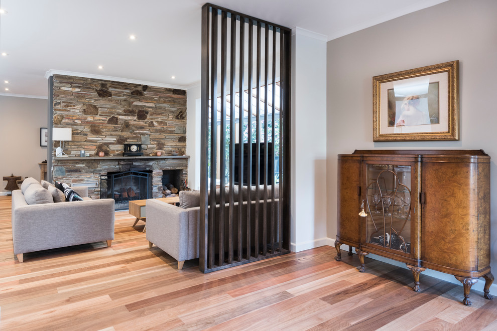 Mittelgroßes, Offenes Eklektisches Wohnzimmer mit grauer Wandfarbe, braunem Holzboden, Kamin und Kaminumrandung aus Stein in Melbourne