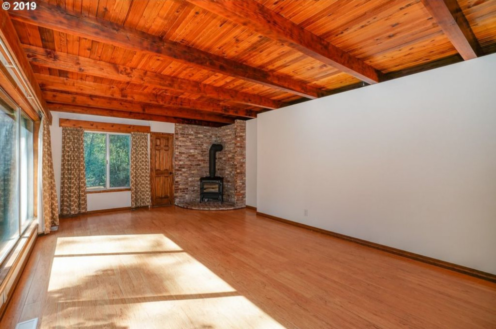 Immagine di un soggiorno moderno con pareti bianche, pavimento in laminato e soffitto in legno