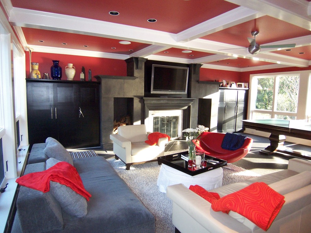 Cette photo montre un salon ouvert avec un mur rouge, sol en béton ciré, une cheminée standard, un manteau de cheminée en béton et un sol gris.