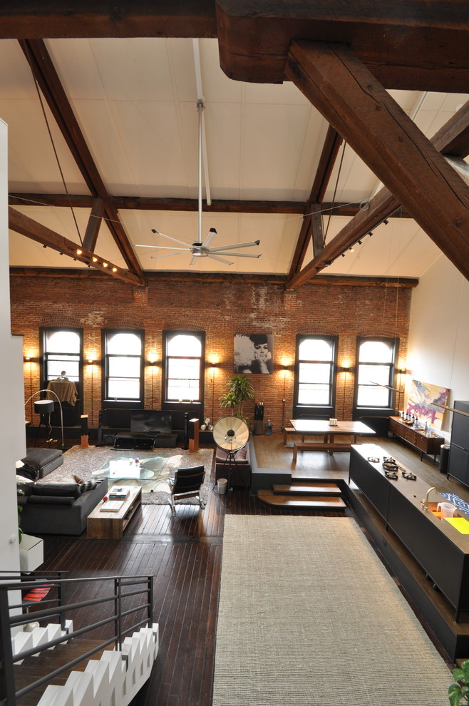 Modelo de salón abierto industrial de tamaño medio sin chimenea con paredes marrones, suelo de madera oscura, suelo marrón y alfombra