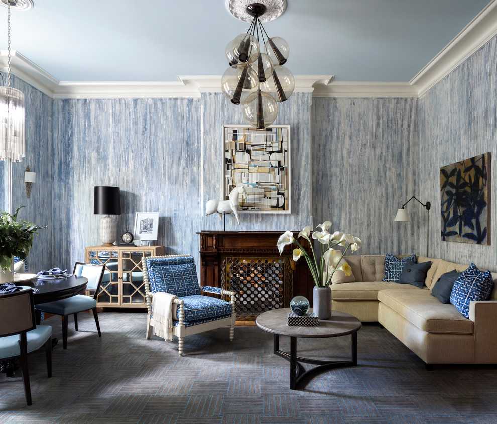 Klassisk inredning av ett vardagsrum, med blå väggar, heltäckningsmatta, en standard öppen spis och grått golv