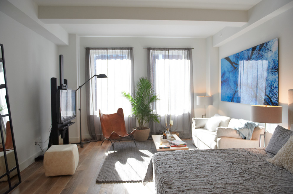Modelo de salón para visitas abierto actual de tamaño medio con paredes blancas y suelo de madera en tonos medios