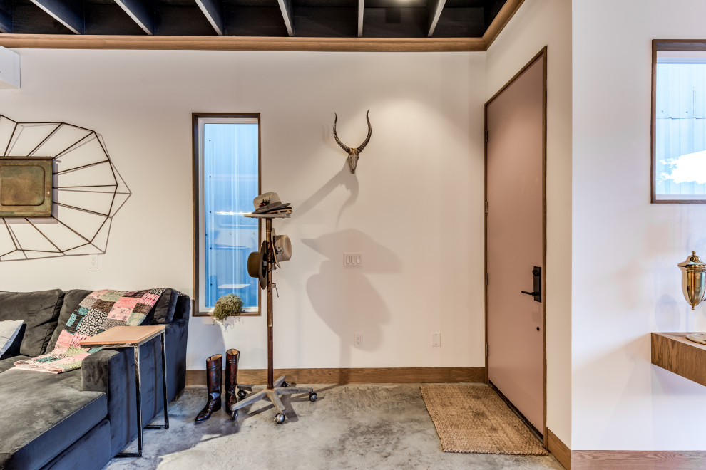 На фото: открытая гостиная комната среднего размера в стиле фьюжн с белыми стенами, бетонным полом, скрытым телевизором, серым полом и балками на потолке