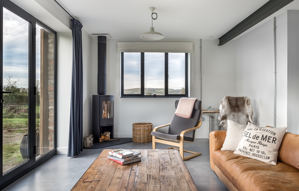 This is an example of a farmhouse formal and grey and brown enclosed living room in Other with white walls, concrete flooring, a wood burning stove, a metal fireplace surround and grey floors.