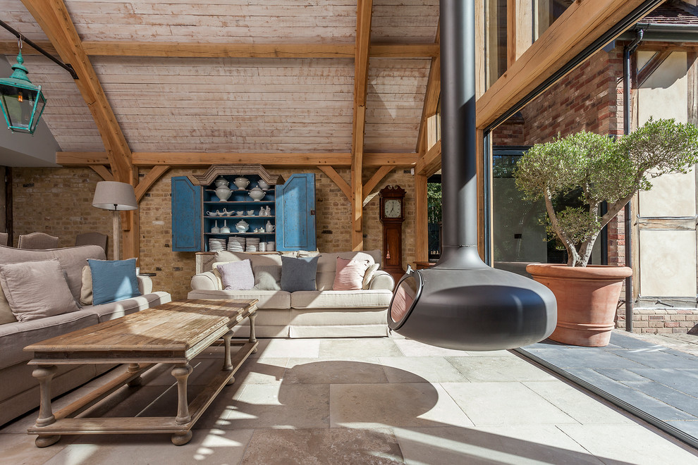 Ejemplo de salón abierto de estilo de casa de campo con chimeneas suspendidas y suelo gris