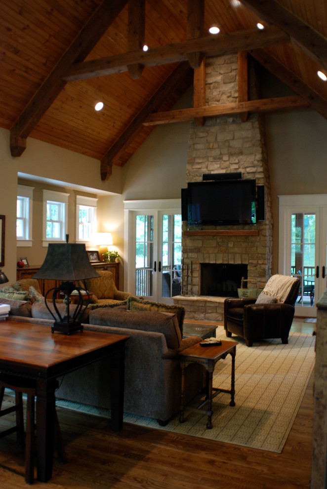 Пример оригинального дизайна: гостиная комната в классическом стиле с стандартным камином, фасадом камина из камня и телевизором на стене