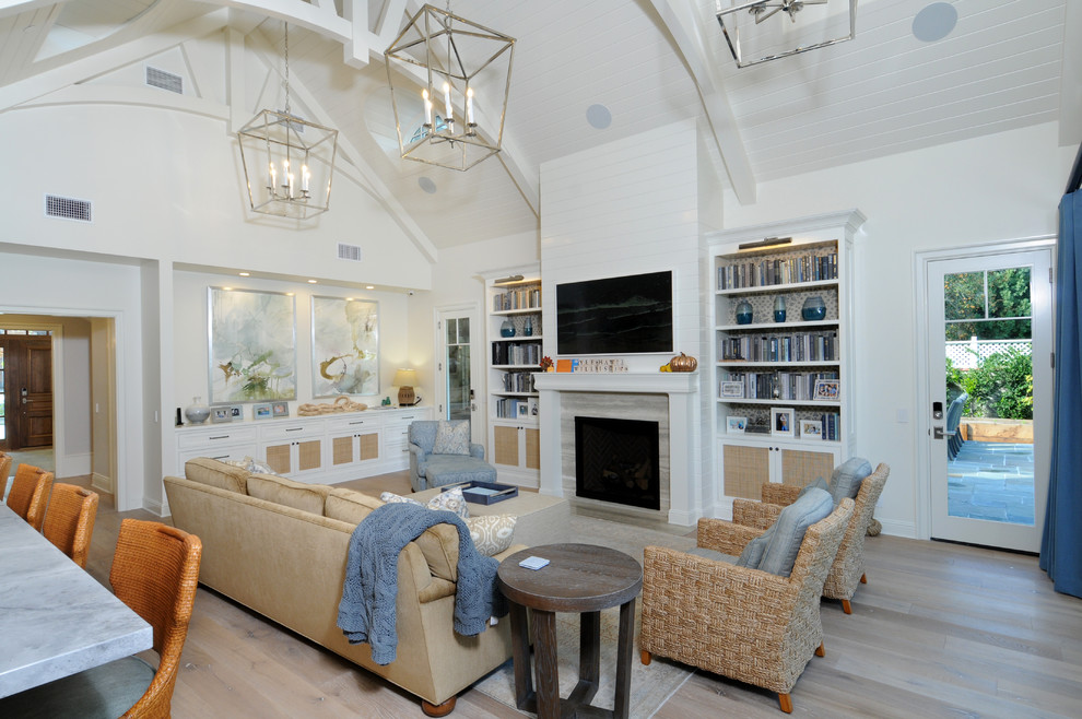 На фото: открытая гостиная комната в морском стиле с стандартным камином, фасадом камина из плитки, белыми стенами, светлым паркетным полом, бежевым полом и синими шторами