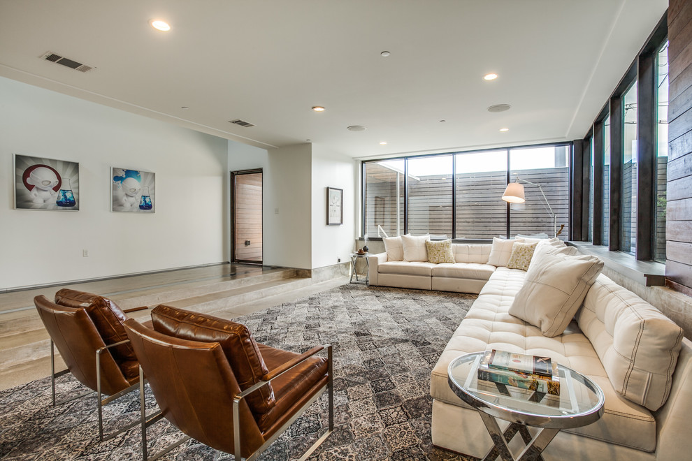Modern open plan living room in Dallas with white walls and concrete flooring.
