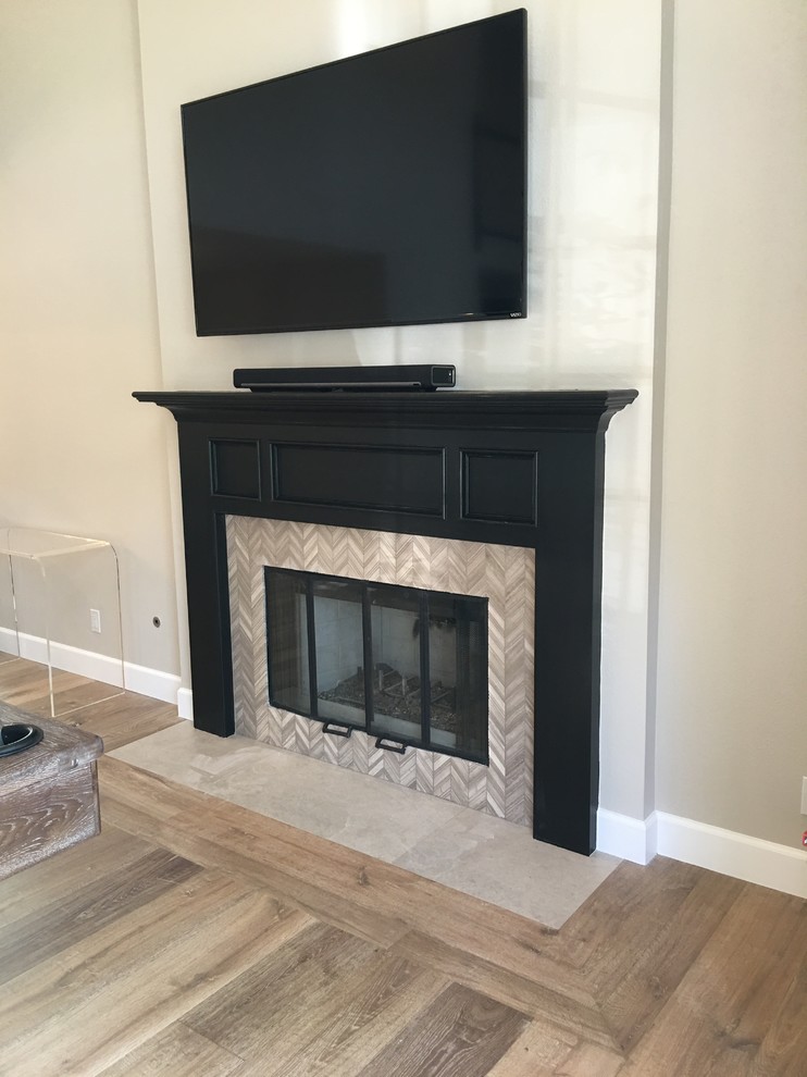 This is an example of a medium sized classic formal enclosed living room in Los Angeles with grey walls, medium hardwood flooring, a standard fireplace, a tiled fireplace surround and a wall mounted tv.